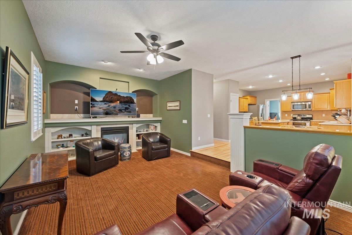 Living room featuring a glass covered fireplace and ceiling fan