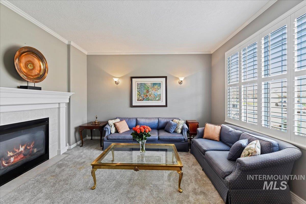 Living room featuring crown molding, carpet flooring, a tile fireplace, and a textured ceiling