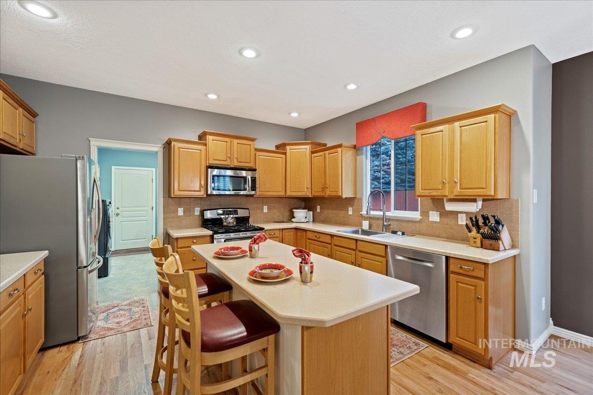 Kitchen featuring light wood-type flooring, appliances with stainless steel finishes, backsplash, and recessed lighting