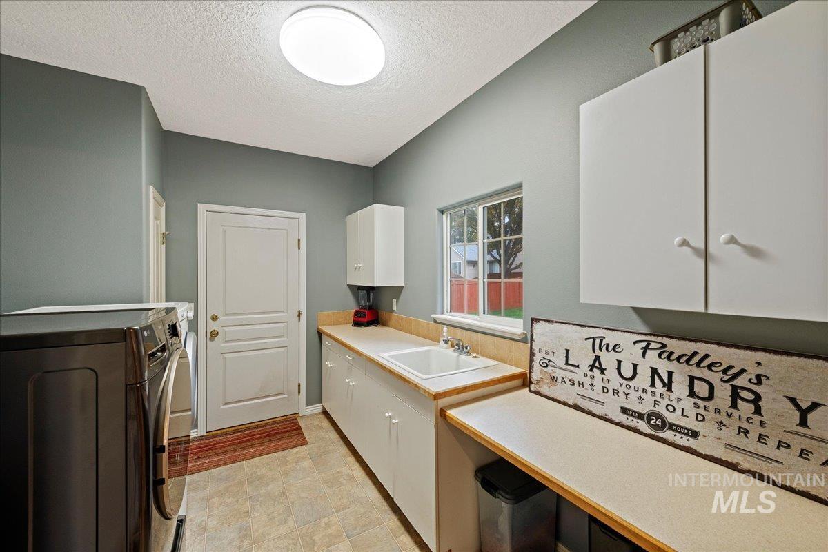 Laundry area featuring a textured ceiling, cabinet space, and washer and clothes dryer