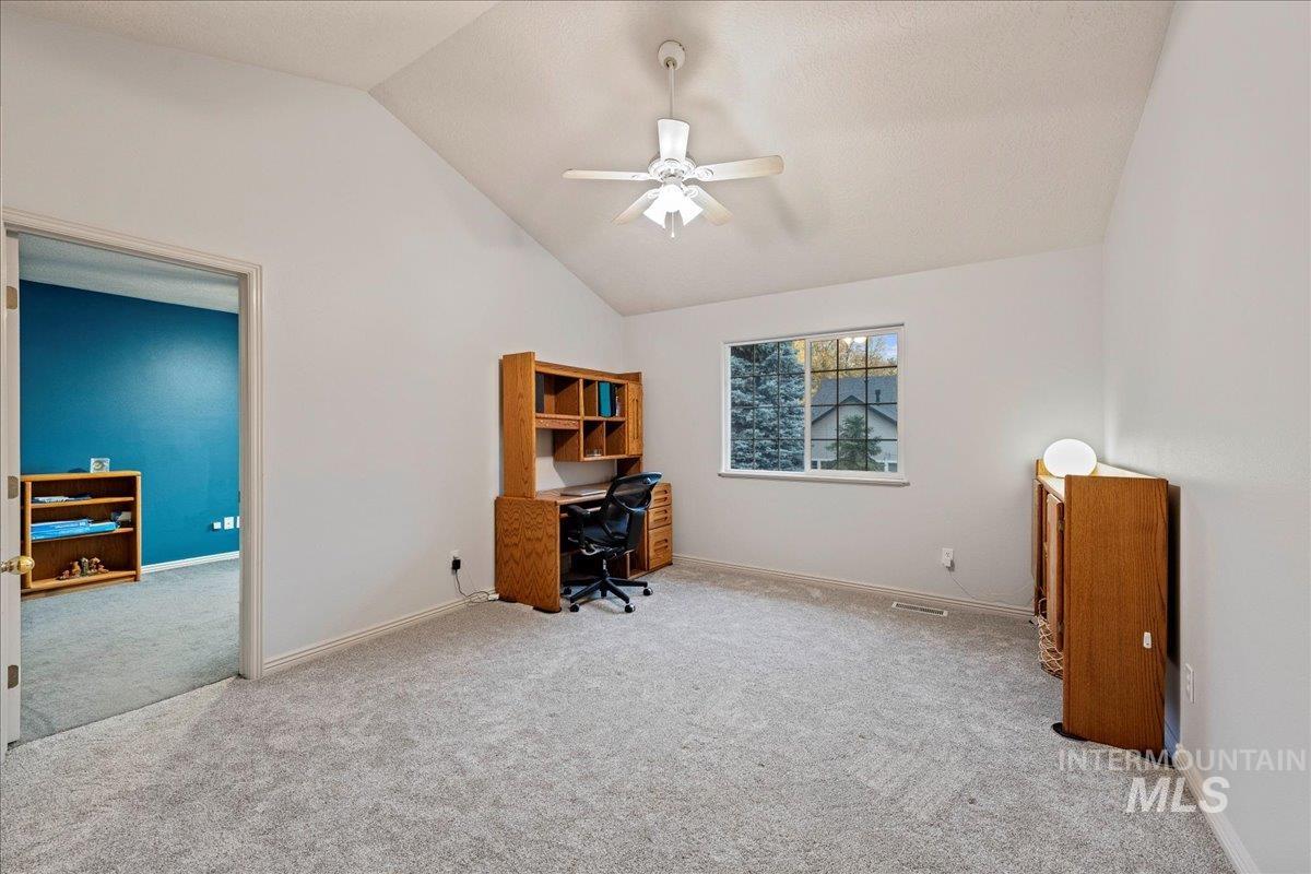 Home office with lofted ceiling, ceiling fan, and carpet flooring