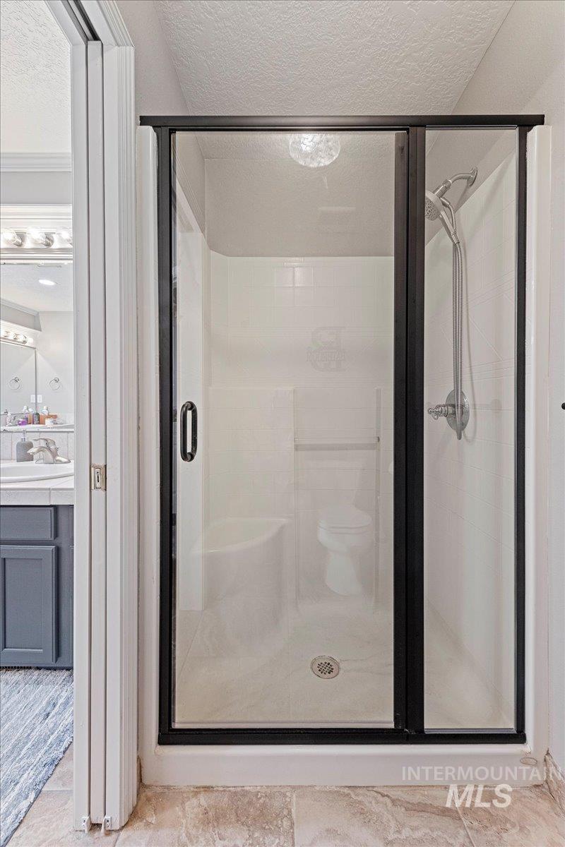 Full bath featuring a textured ceiling, a stall shower, and tile patterned floors