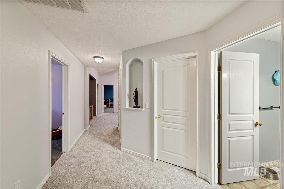 Hallway with a textured ceiling and light carpet