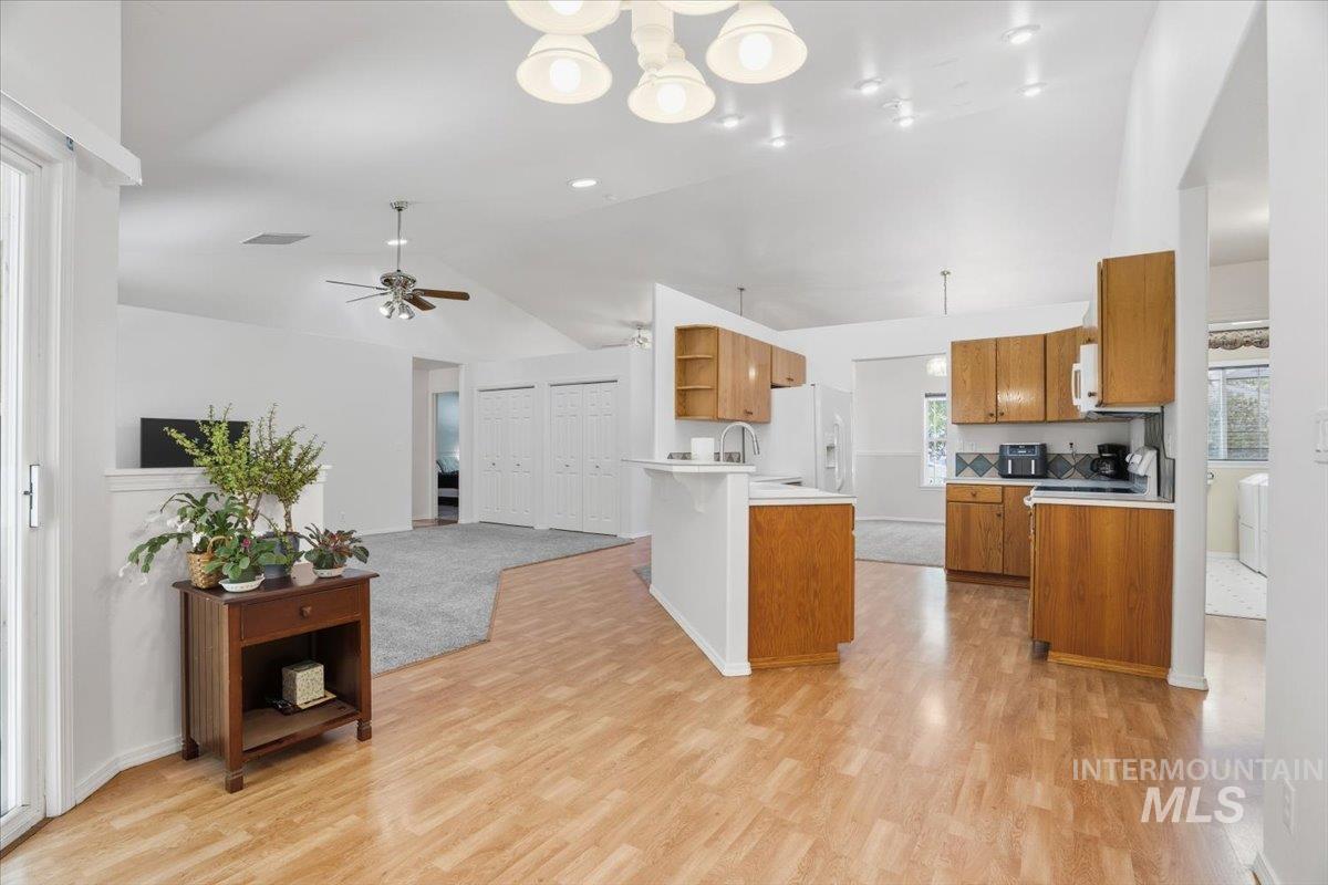 Kitchen with wood cabinets, lofted ceiling, light countertops, open floor plan