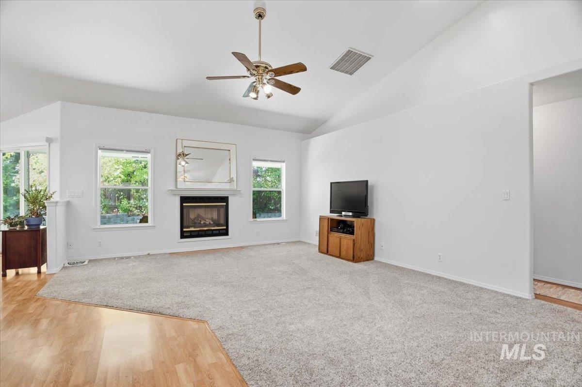 Living room featuring a ceiling fan, Laminate flooring, high vaulted ceiling, fireplace, and professionally cleaned carpet