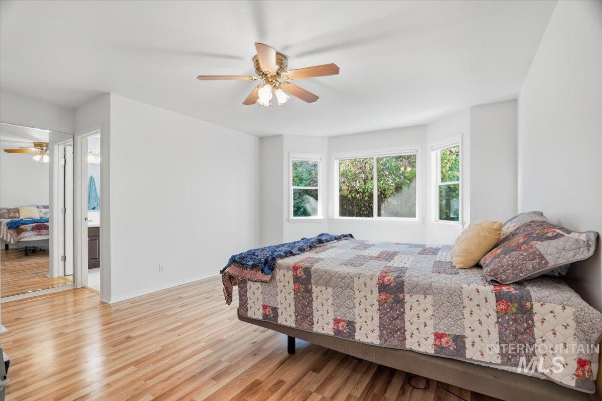 Bedroom with laminate flooring, ceiling fan, ensuite bathroom, walk-in closet