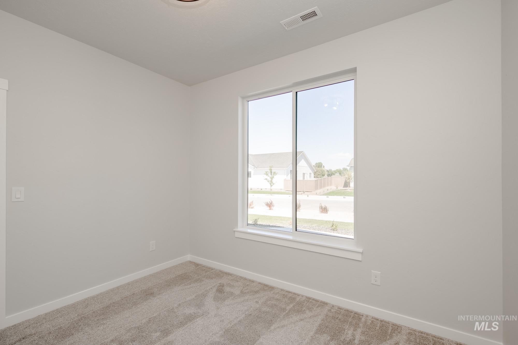Spare room featuring light carpet and baseboards