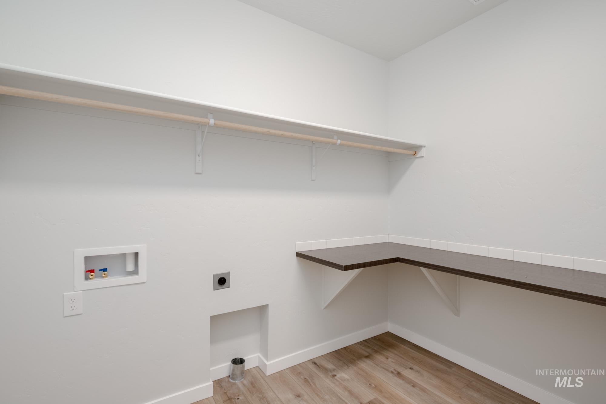 Washroom with hookup for a washing machine, hookup for an electric dryer, and light wood-type flooring