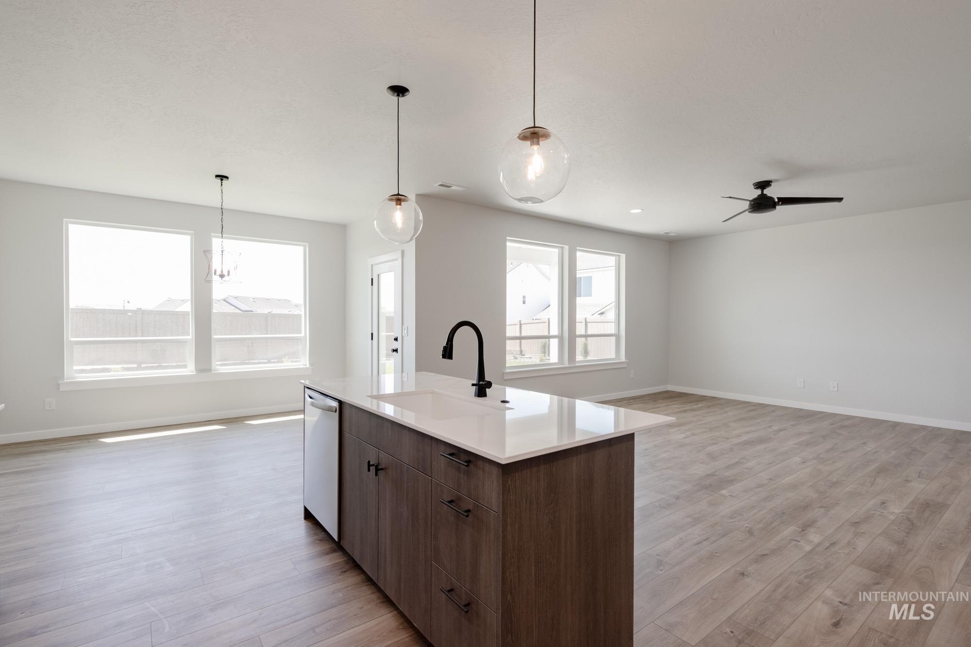 Kitchen with open floor plan, light wood finished floors, light countertops, and a center island with sink