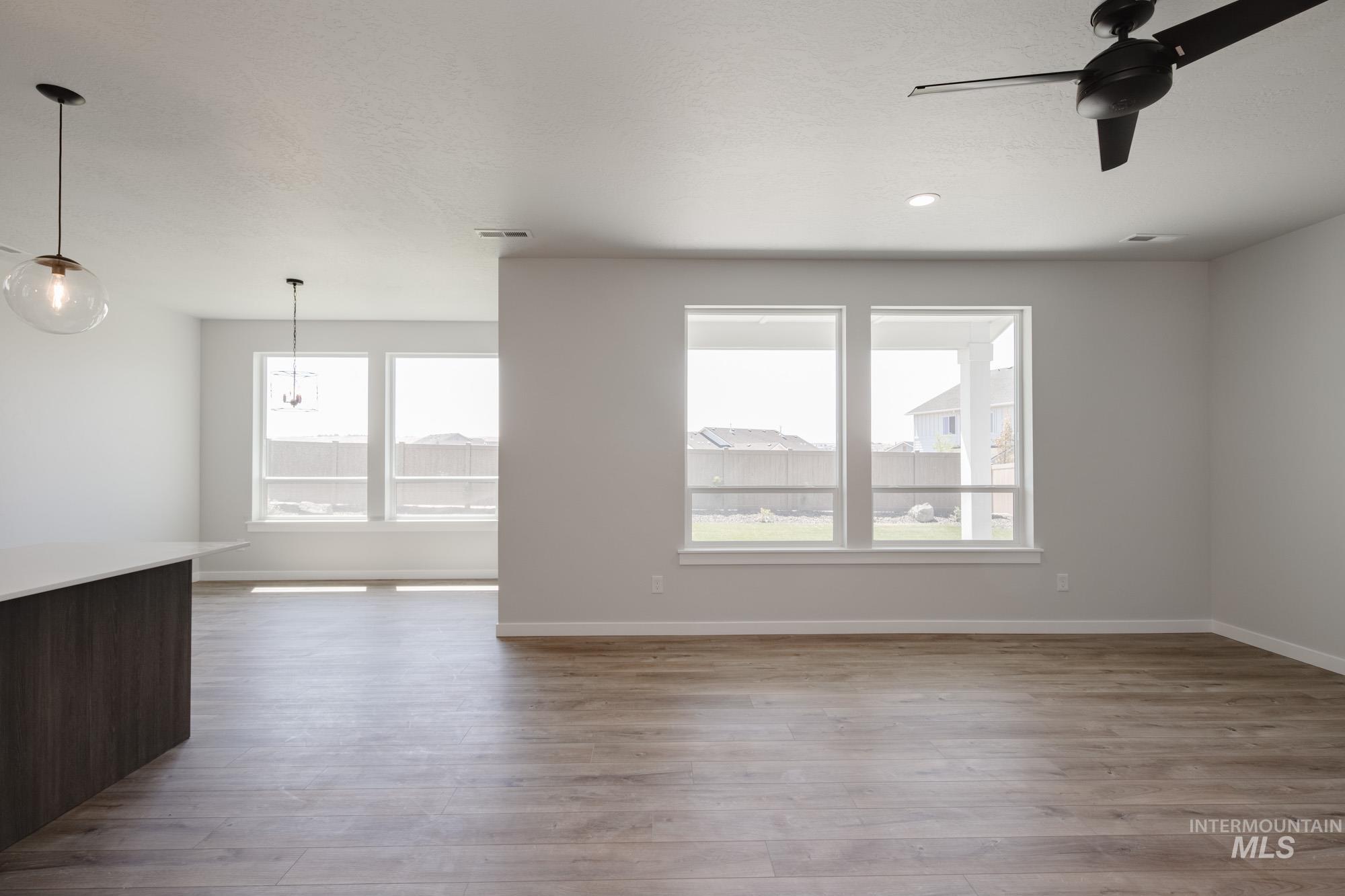 Unfurnished room featuring plenty of natural light, ceiling fan, wood finished floors, and a textured ceiling