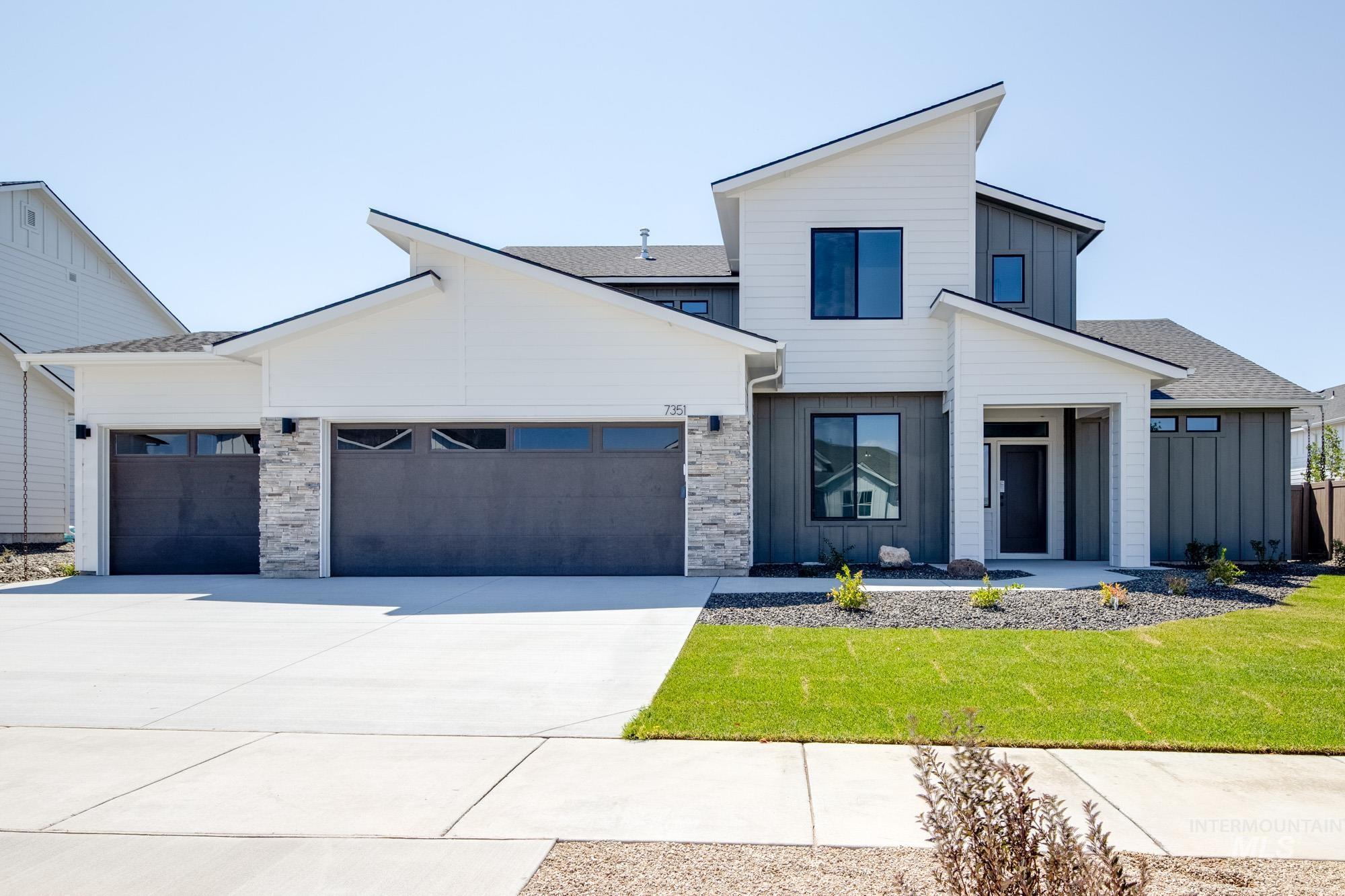 View of front of home featuring board and batten siding, an attached garage, driveway, and a front lawn