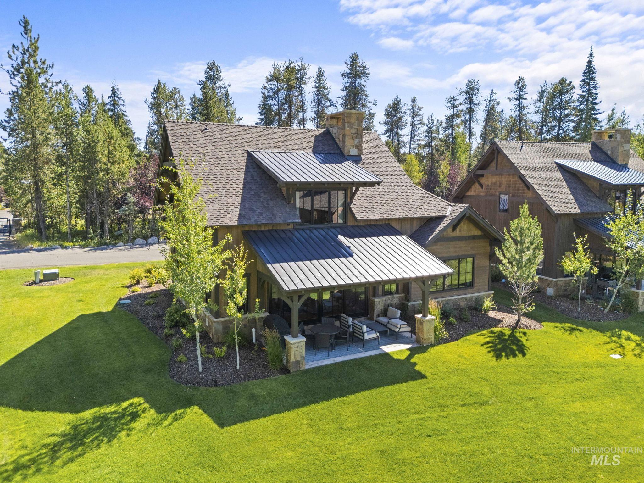 Back of house featuring a standing seam roof, a patio area, a chimney, a metal roof, and a lawn