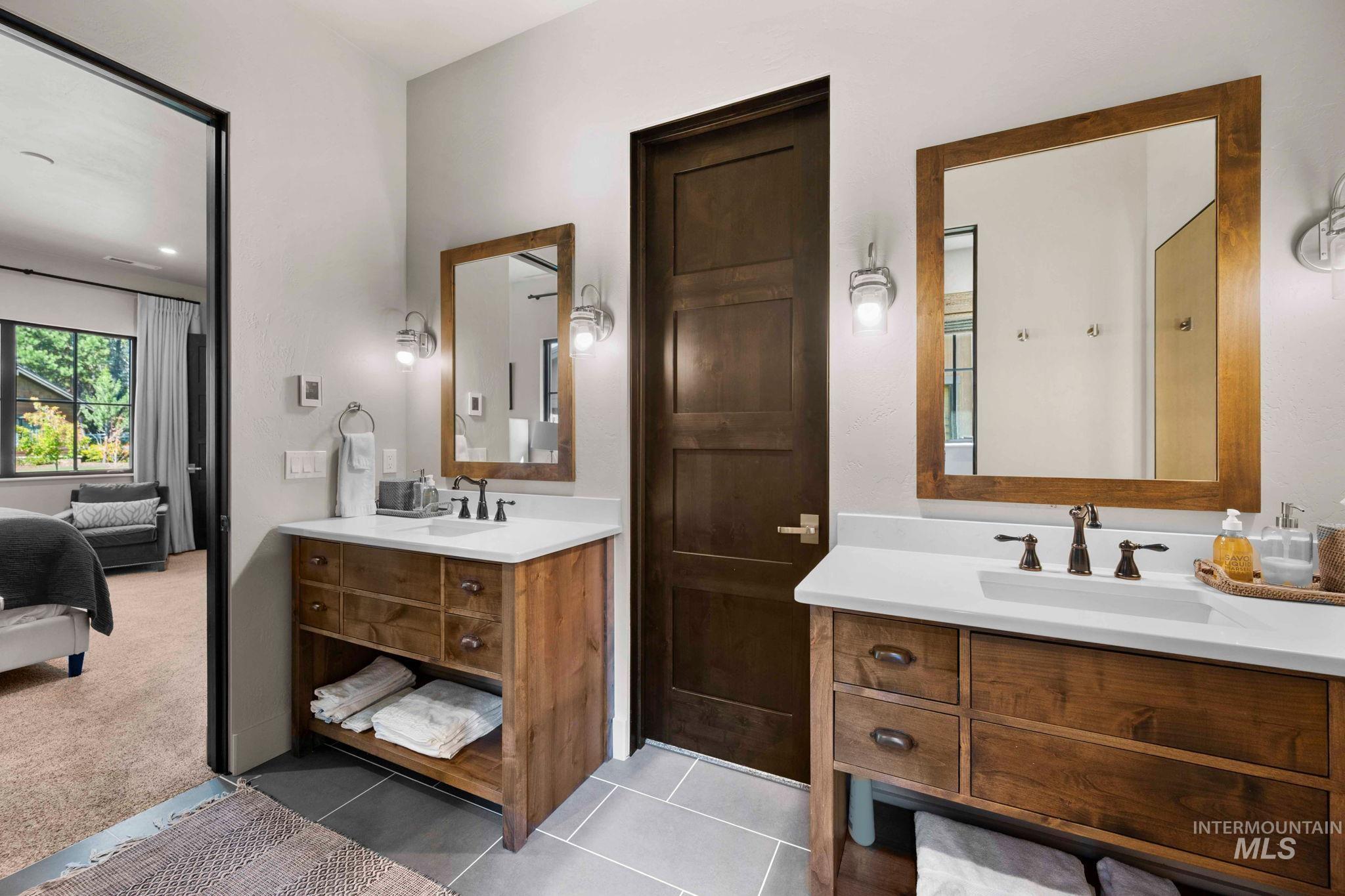Ensuite bathroom featuring two vanities and light tile patterned floors