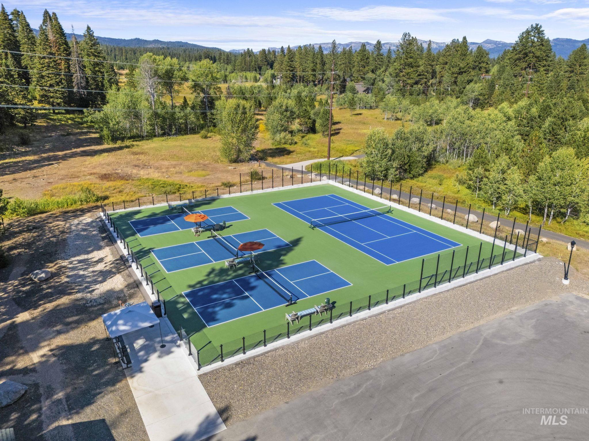 View of tennis court with a forest view