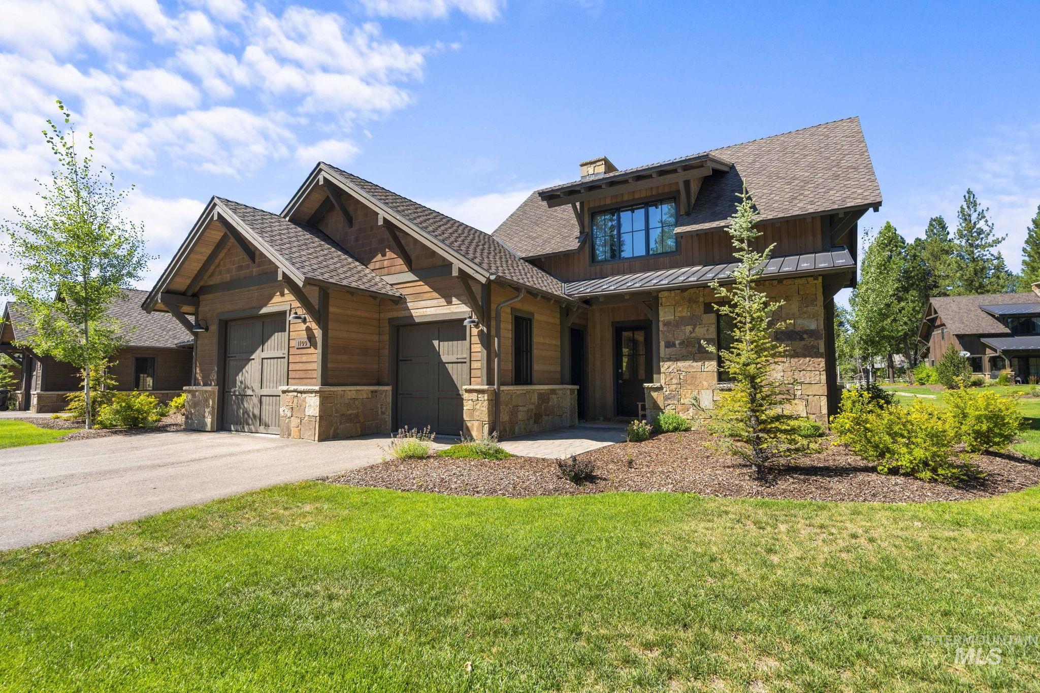 Craftsman-style house with a garage, driveway, a front yard, a chimney, and stone siding