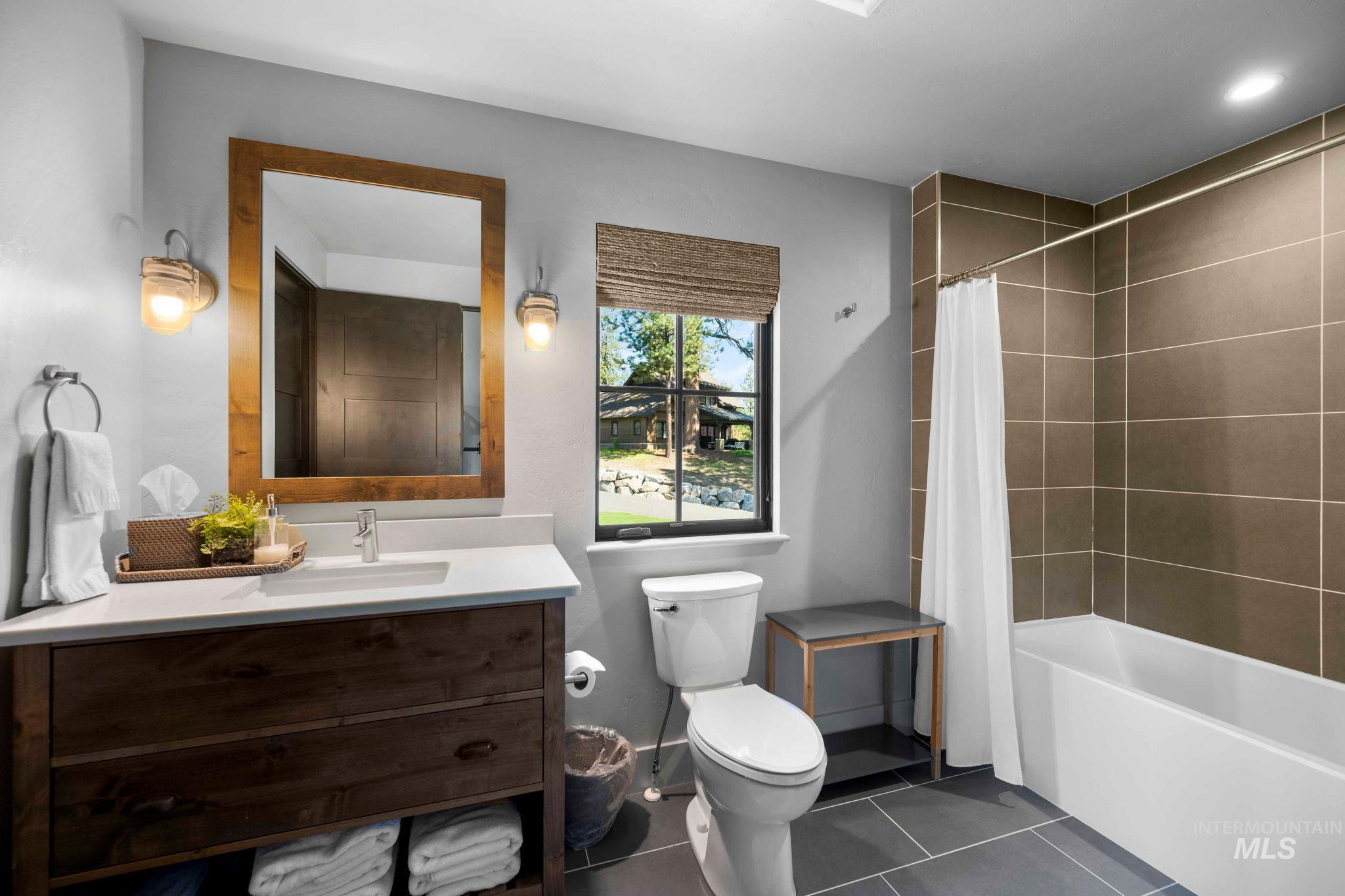 Full bathroom featuring vanity, dark tile patterned floors, and shower / tub combo with curtain