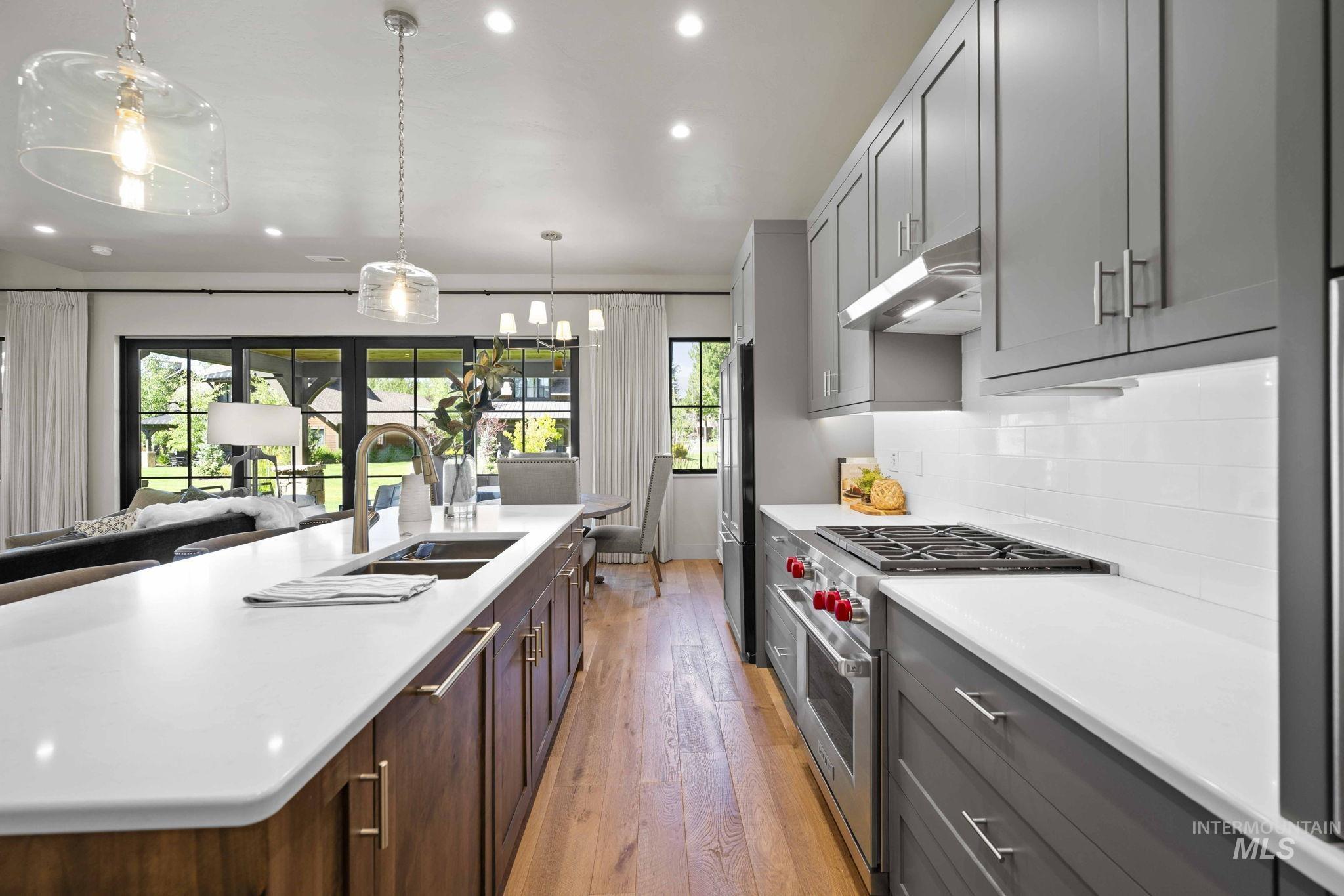 Kitchen with high quality appliances, recessed lighting, light wood-style flooring, decorative light fixtures, and open floor plan