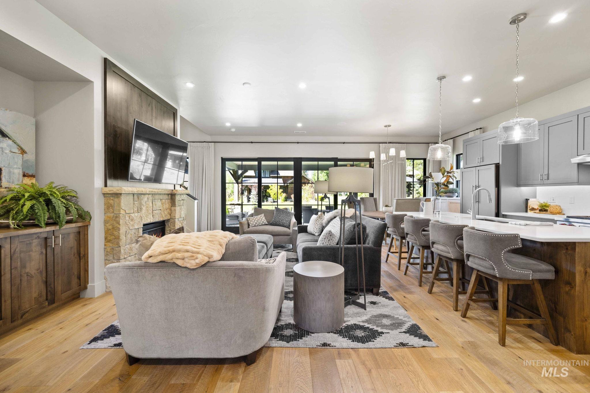 Living area featuring light wood-style floors, a stone fireplace, and recessed lighting