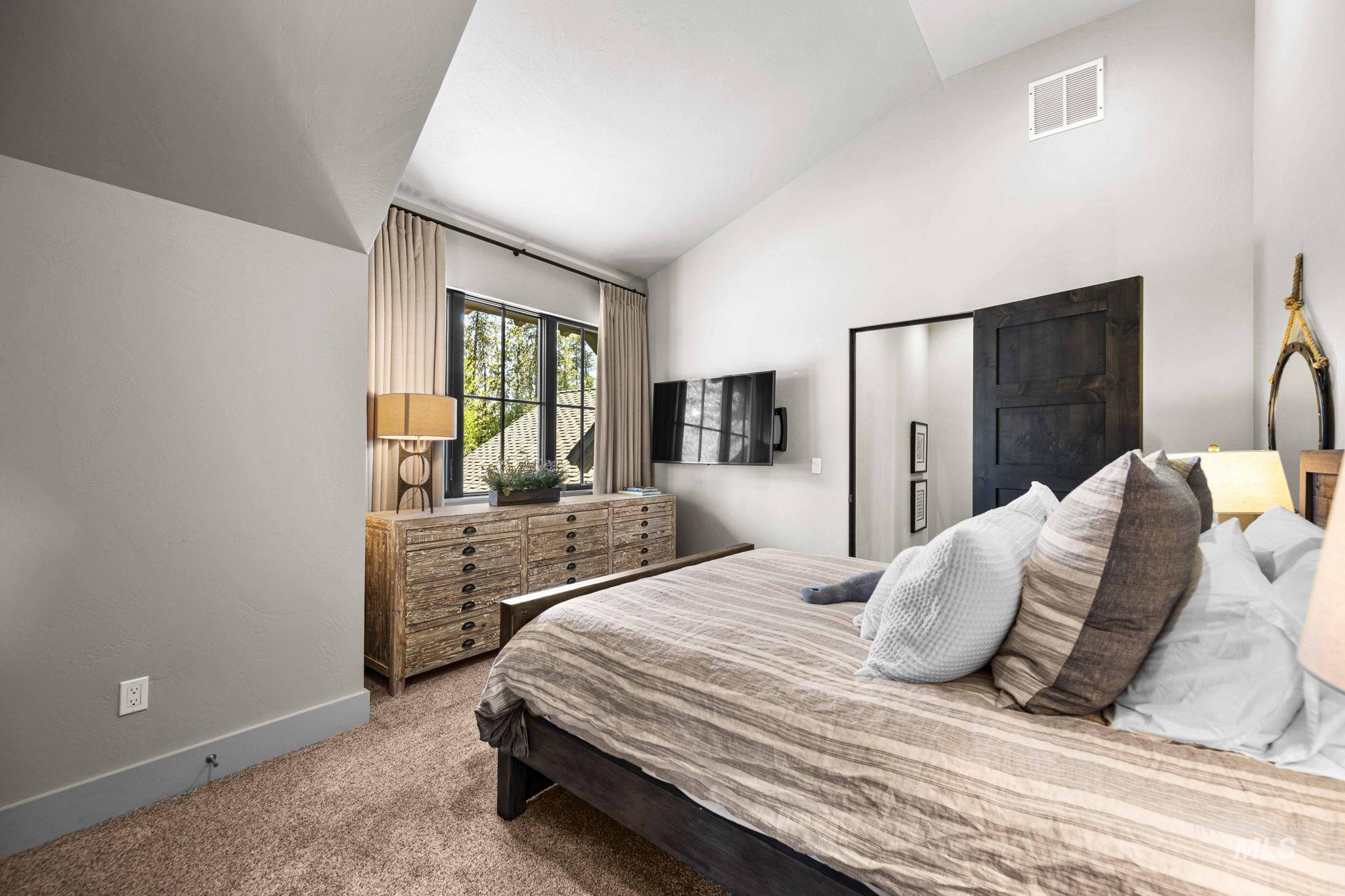 Carpeted bedroom with baseboards and high vaulted ceiling