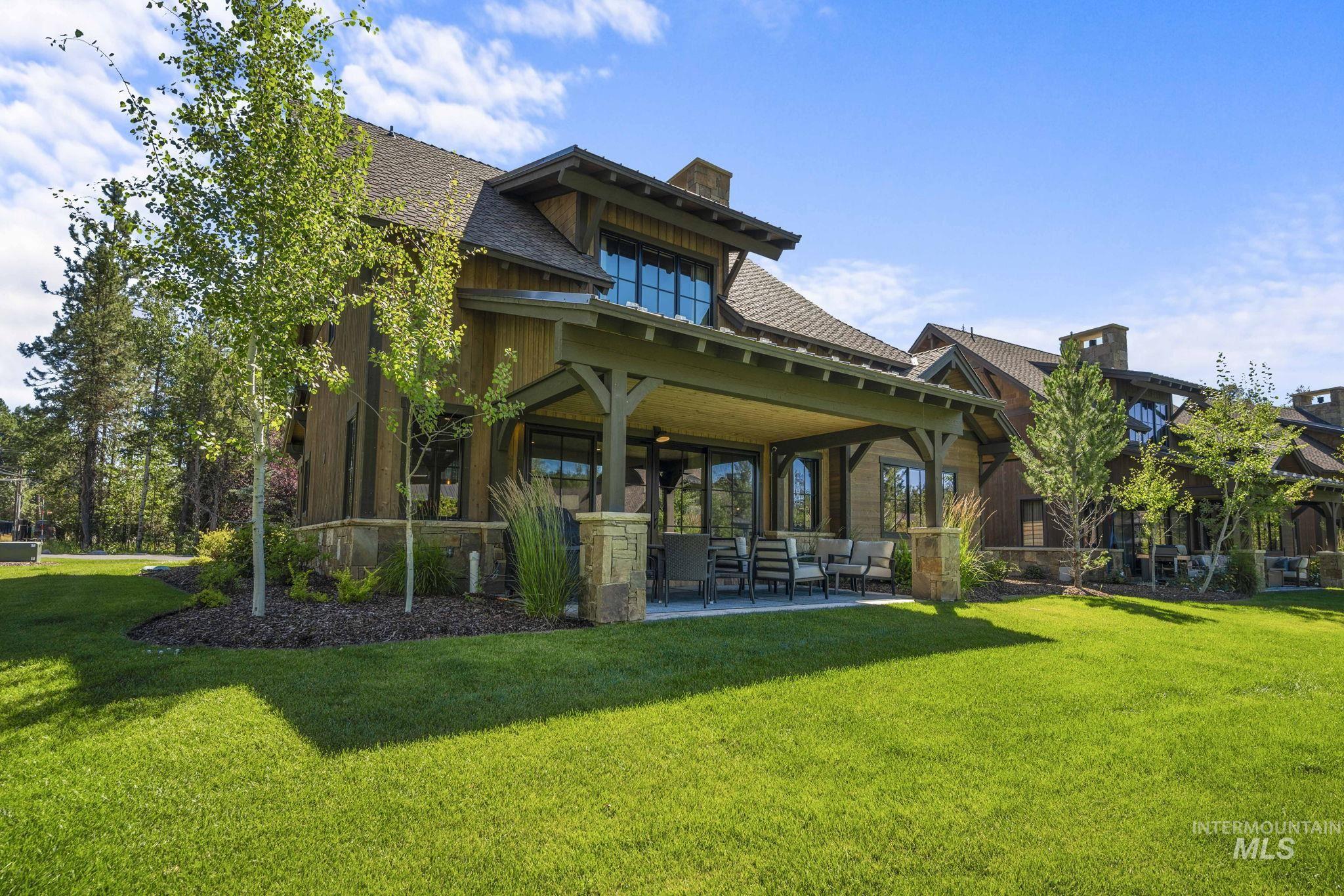 Rear view of house with a patio, a lawn, a shingled roof, and a chimney