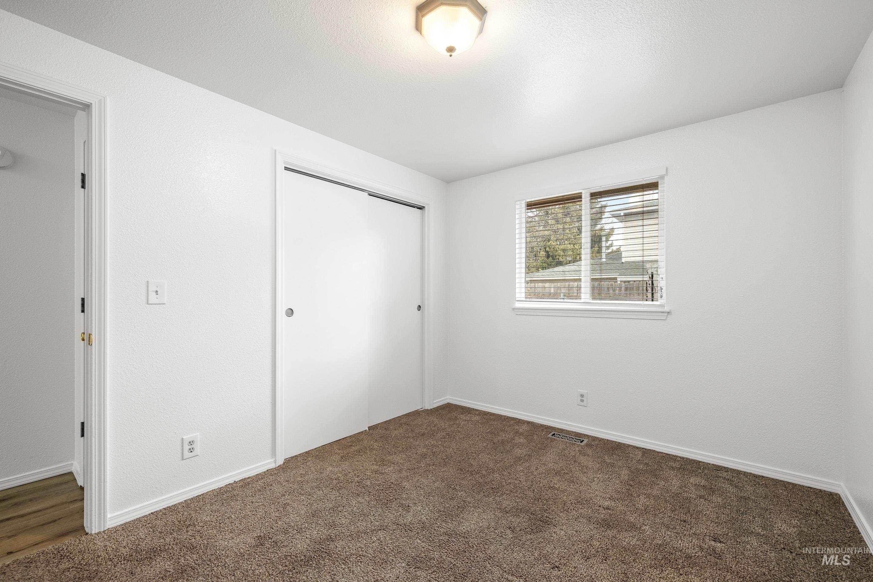 Unfurnished bedroom featuring a closet and dark carpet