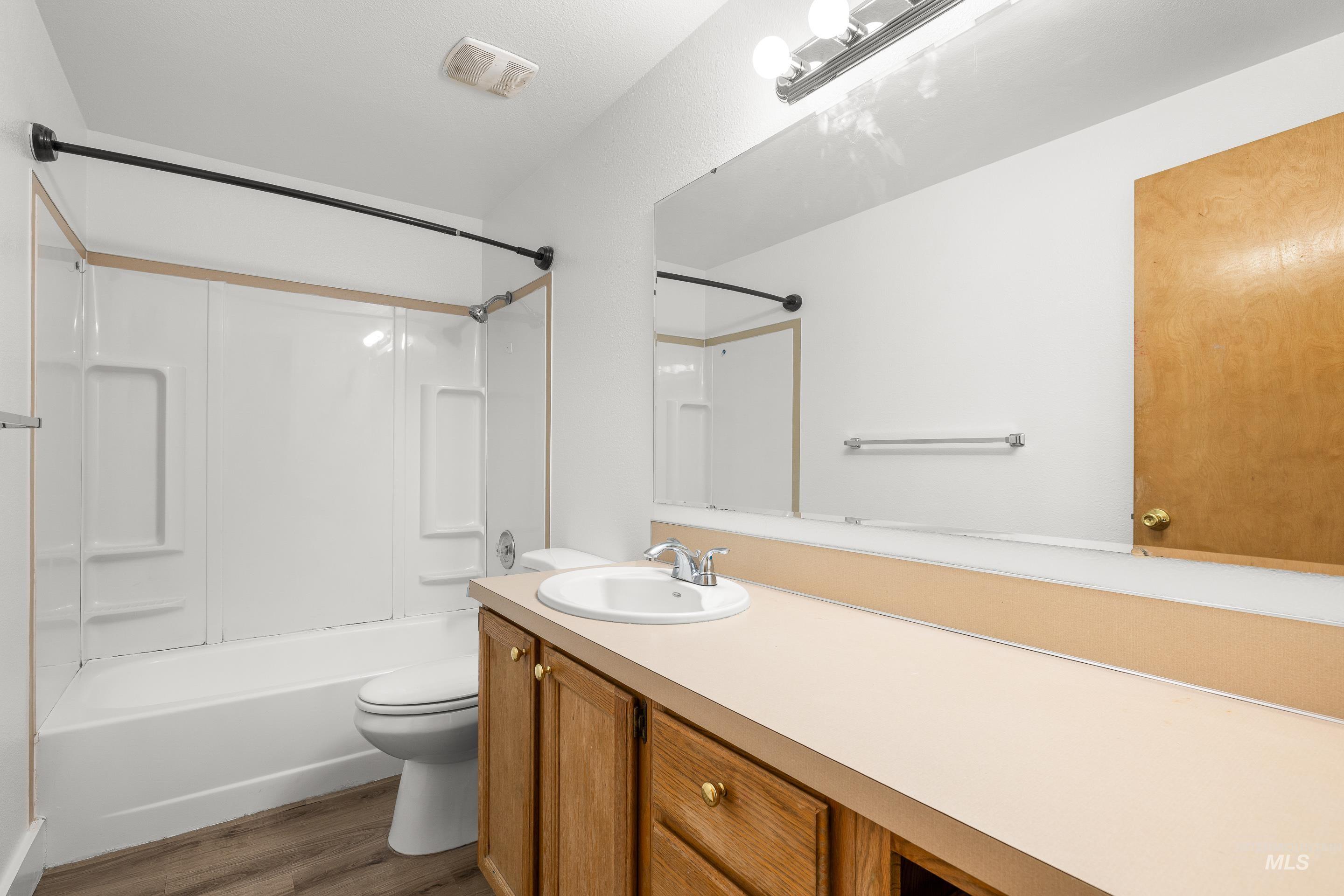 Full bath featuring vanity,  shower combination, and dark wood-type flooring