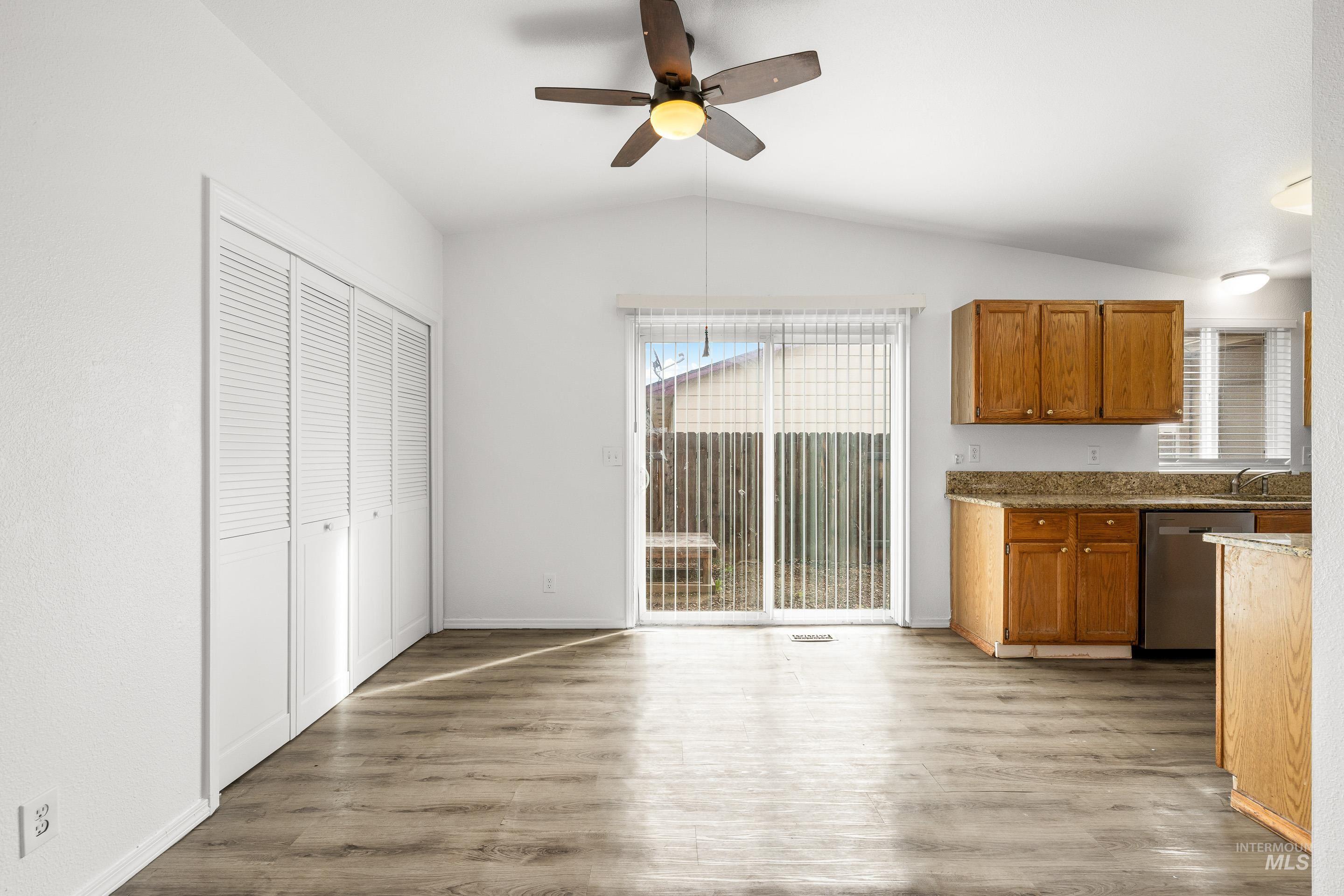Kitchen featuring healthy amount of natural light, light wood-style flooring, dark stone countertops, and wood finish cabinets