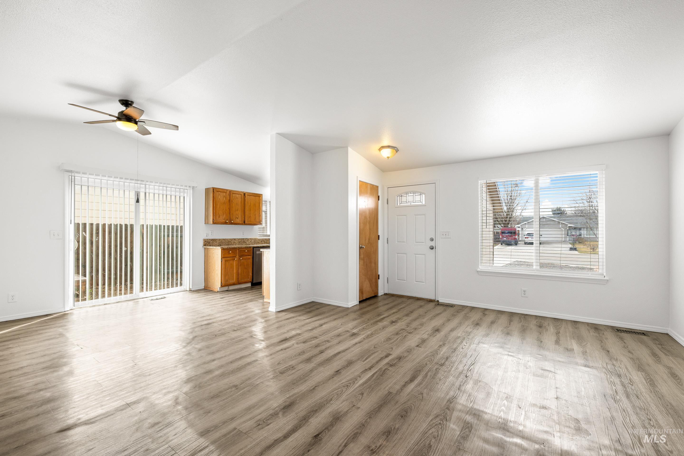 Unfurnished living room with ceiling fan, light wood finished floors, and vaulted ceiling