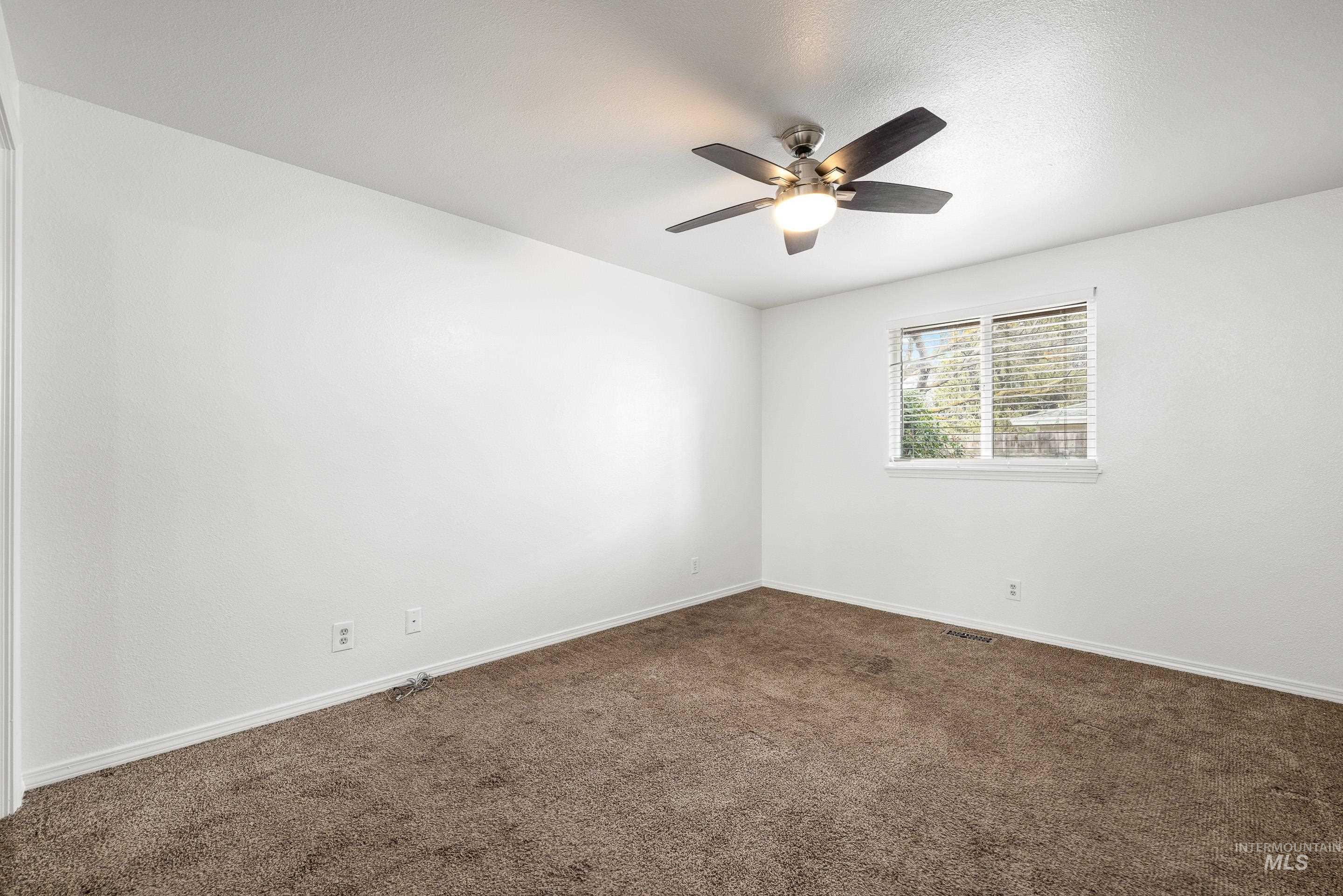 Empty room with dark carpet and ceiling fan
