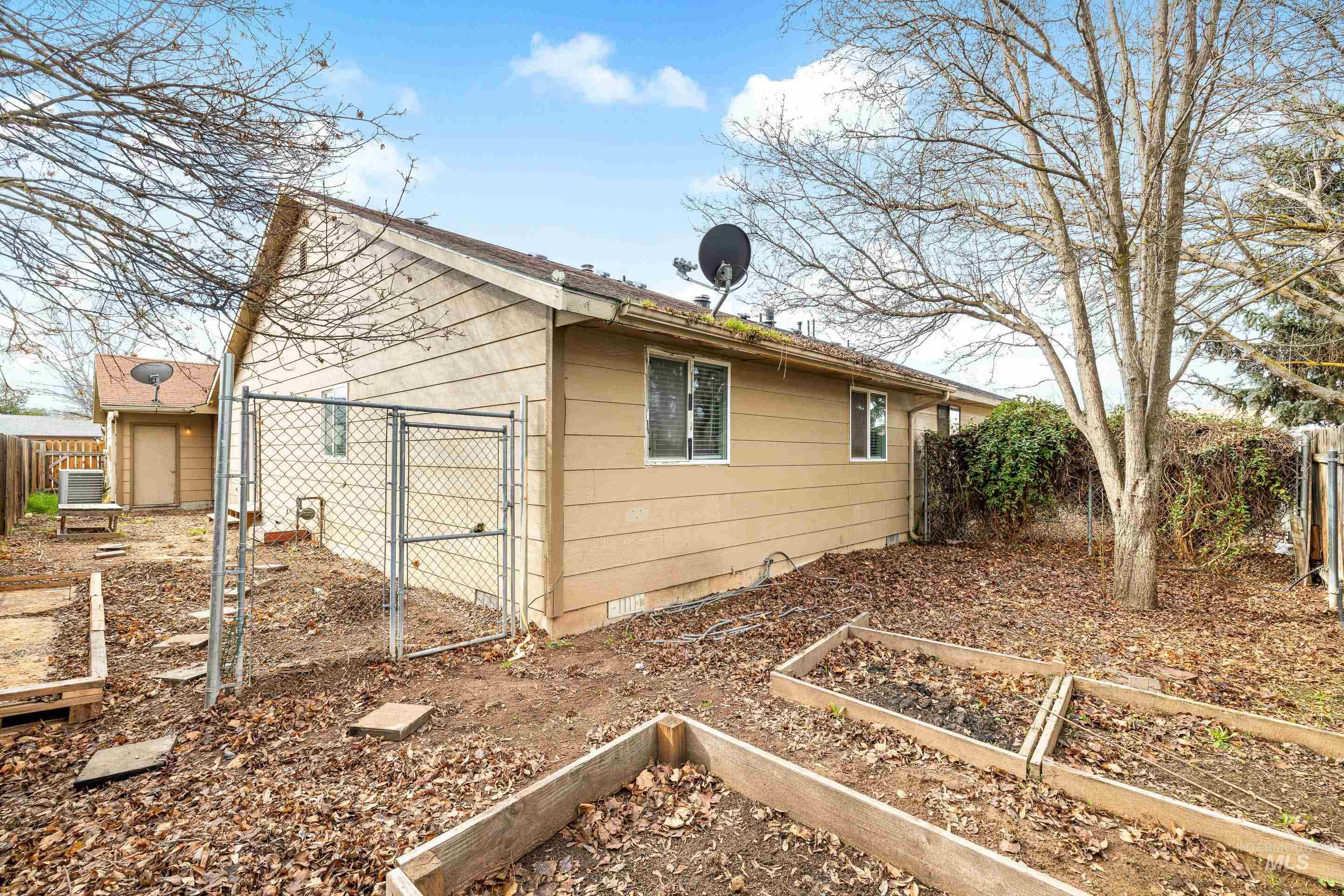 View of property exterior with a fenced backyard, a vegetable garden, and a gate