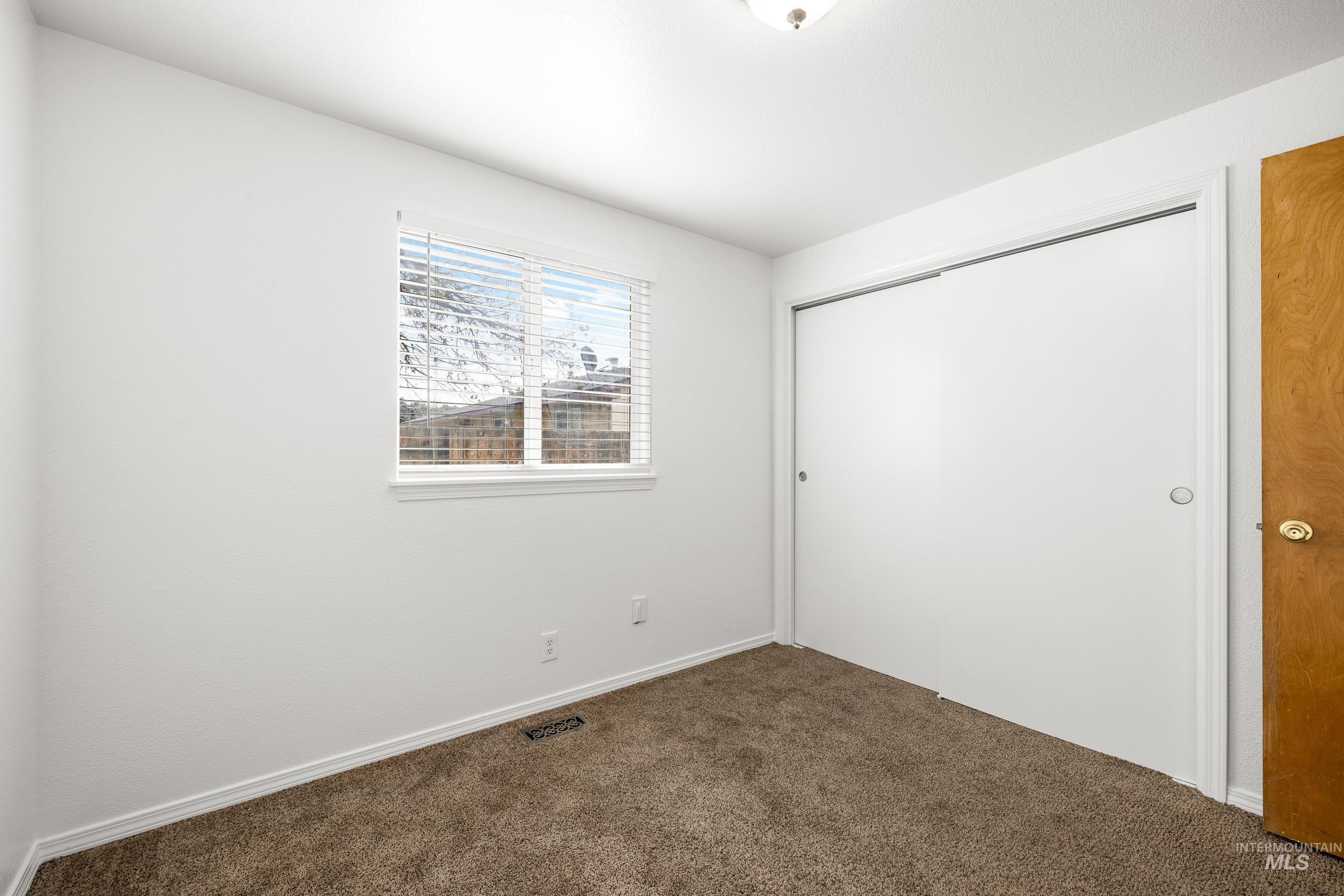 Unfurnished bedroom with a closet and dark carpet