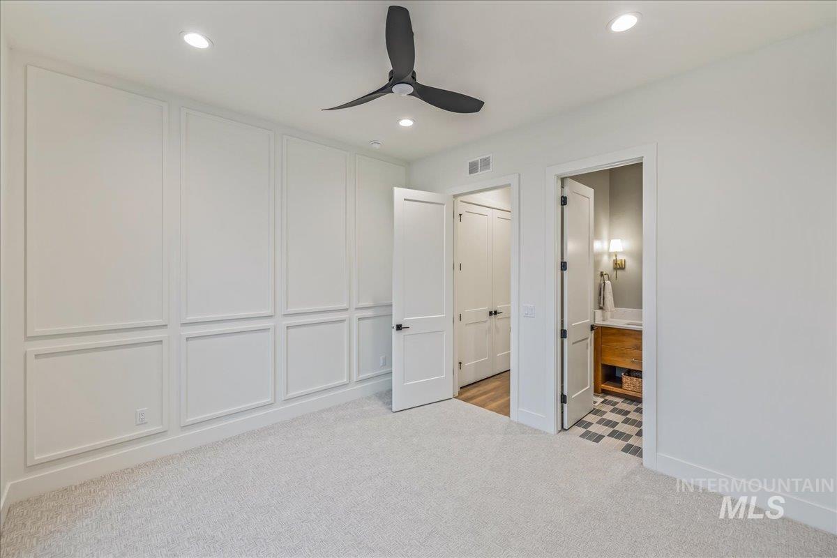Unfurnished bedroom featuring light colored carpet, ceiling fan, recessed lighting, ensuite bathroom, and a decorative wall