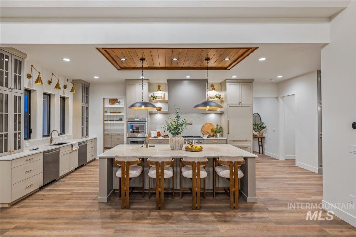 Kitchen featuring a kitchen breakfast bar, pendant lighting, wooden ceiling, light stone counters, and a kitchen island with sink