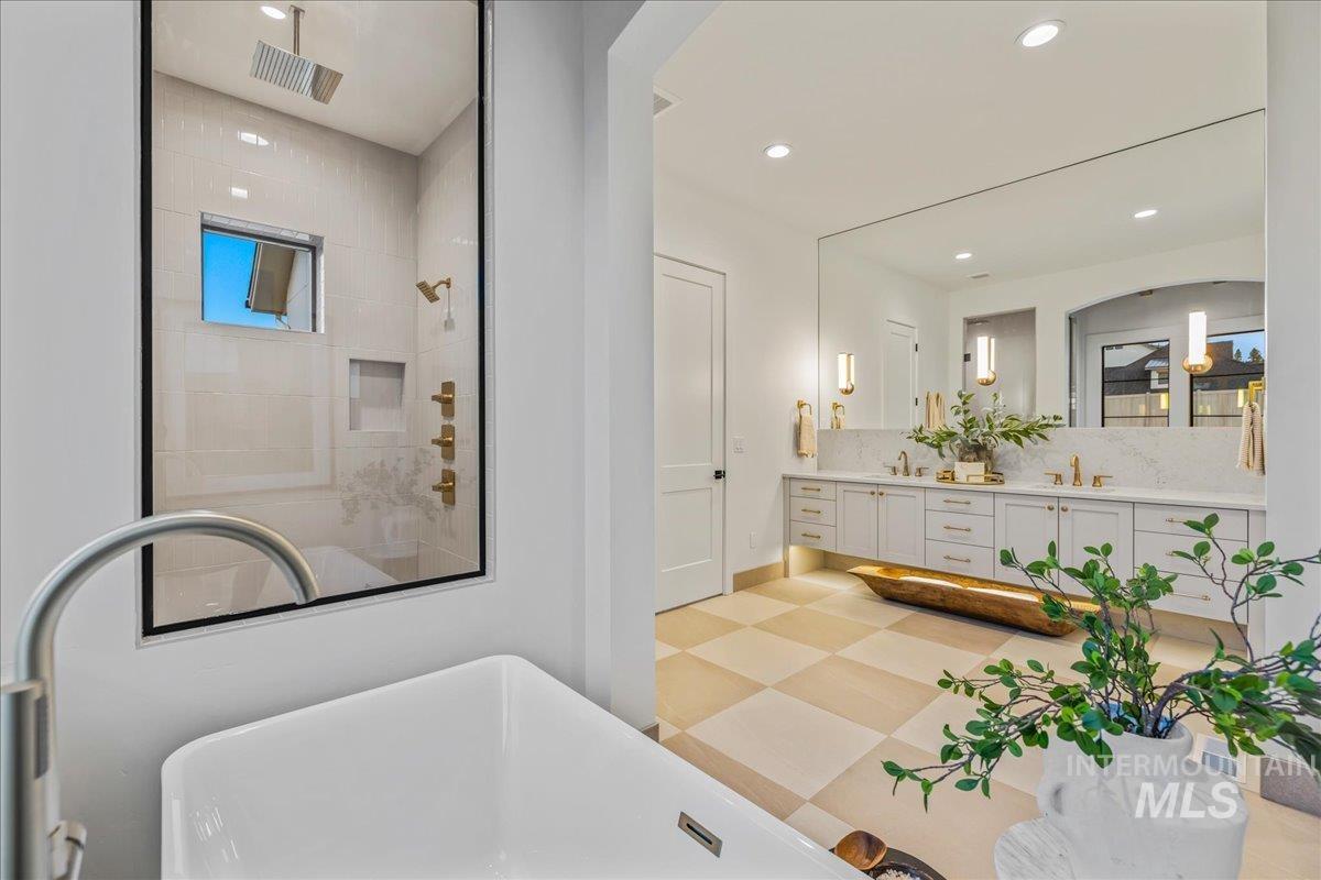 Bathroom with a shower stall, a freestanding bath, double vanity, light floors, and recessed lighting