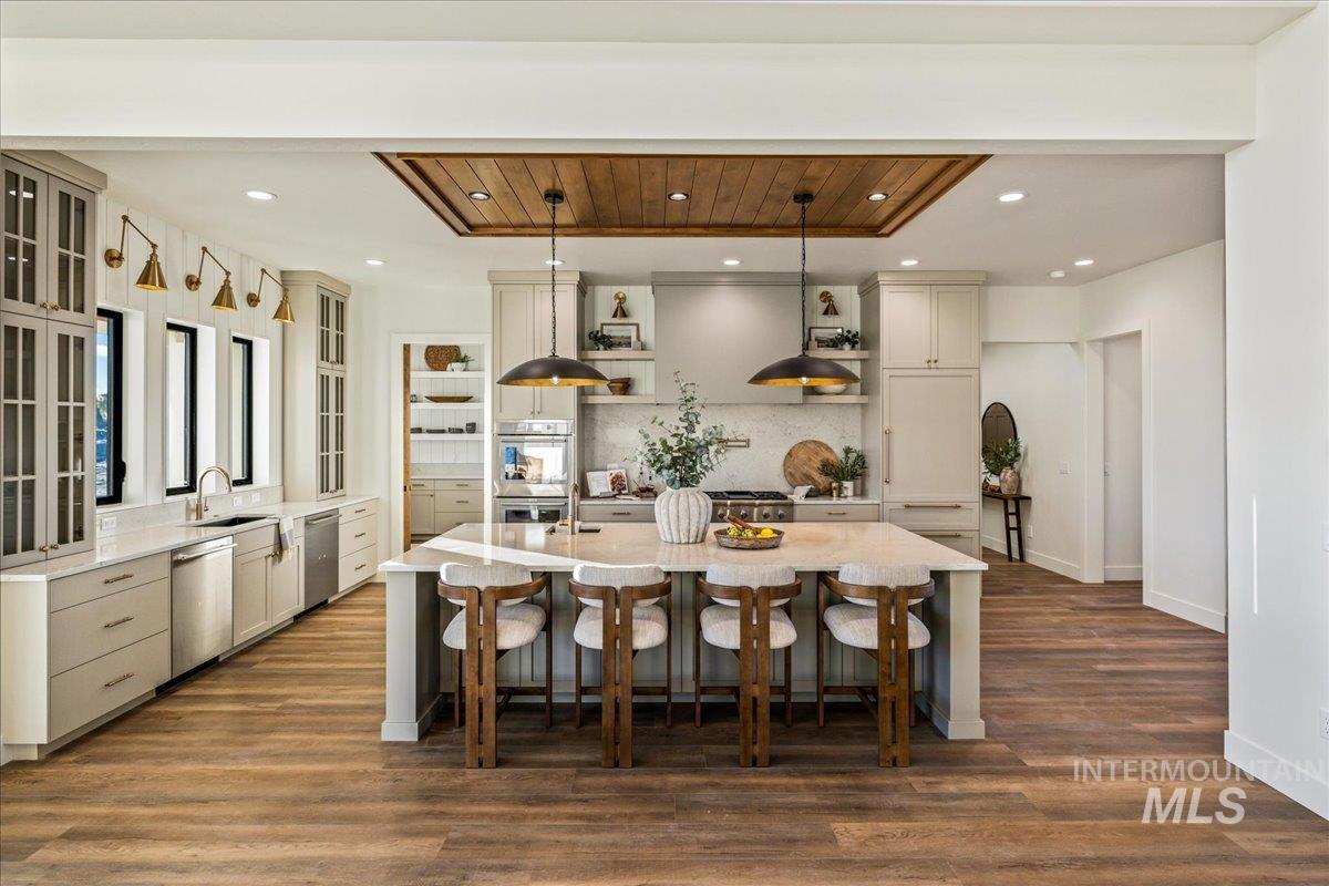 Kitchen featuring pendant lighting, a breakfast bar, light stone countertops, open shelves, and a spacious island