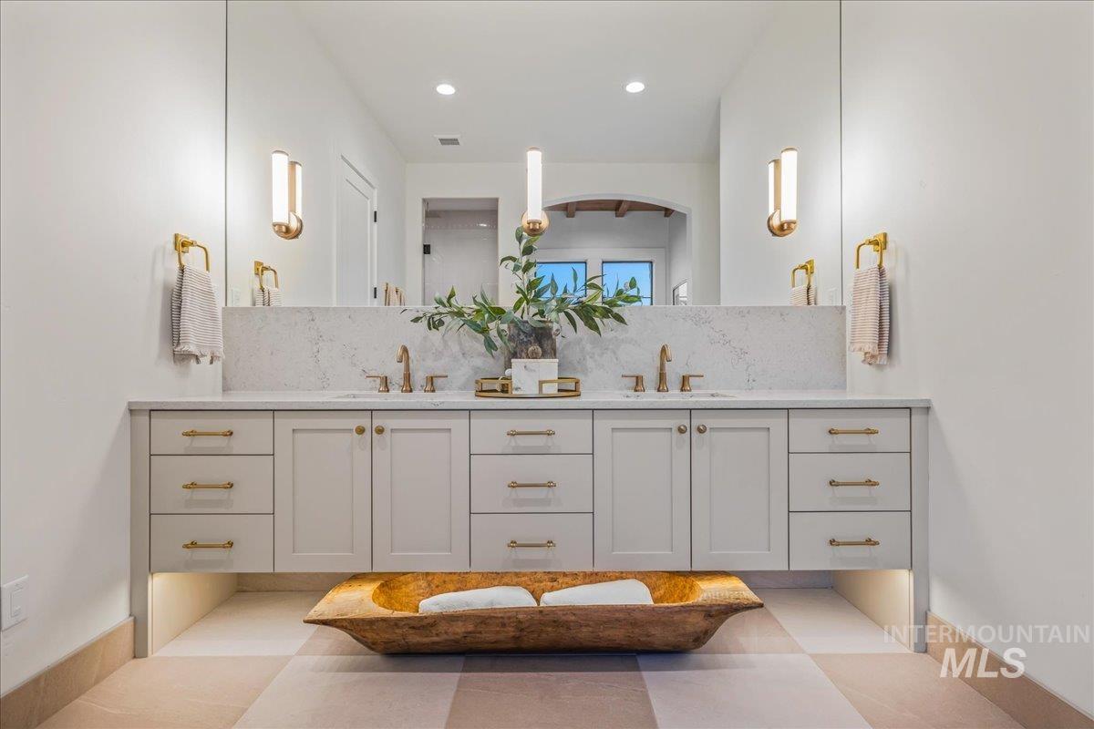 Bathroom featuring double vanity, backsplash, and recessed lighting