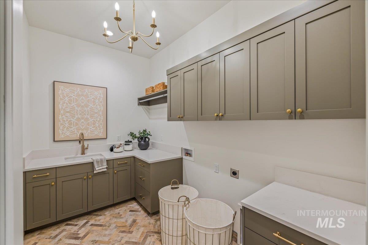 Laundry room featuring washer hookup, electric dryer hookup, cabinet space, and a chandelier