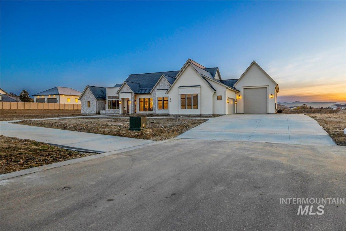 Modern farmhouse with stucco siding, driveway, and an attached garage