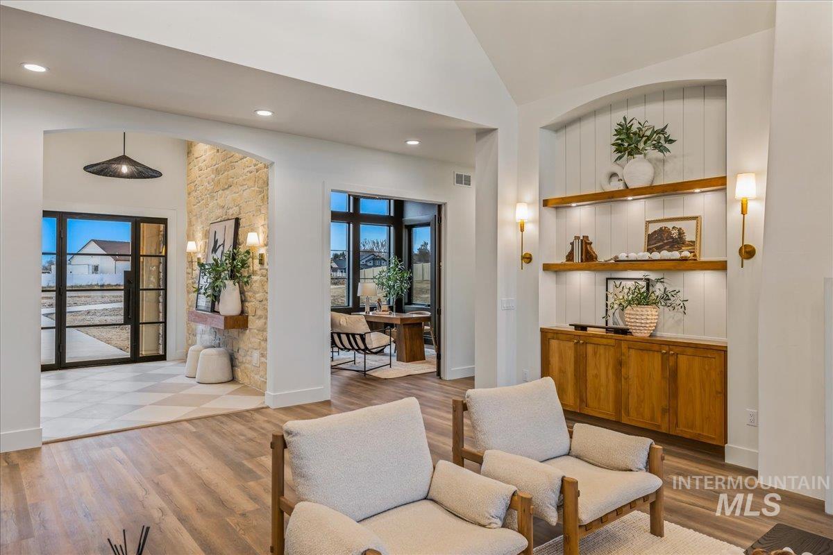 Living room featuring light wood-type flooring, plenty of natural light, recessed lighting, and high vaulted ceiling