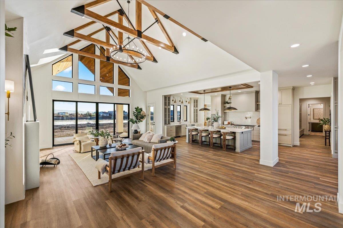 Living room featuring high vaulted ceiling, a chandelier, dark wood finished floors, and beamed ceiling