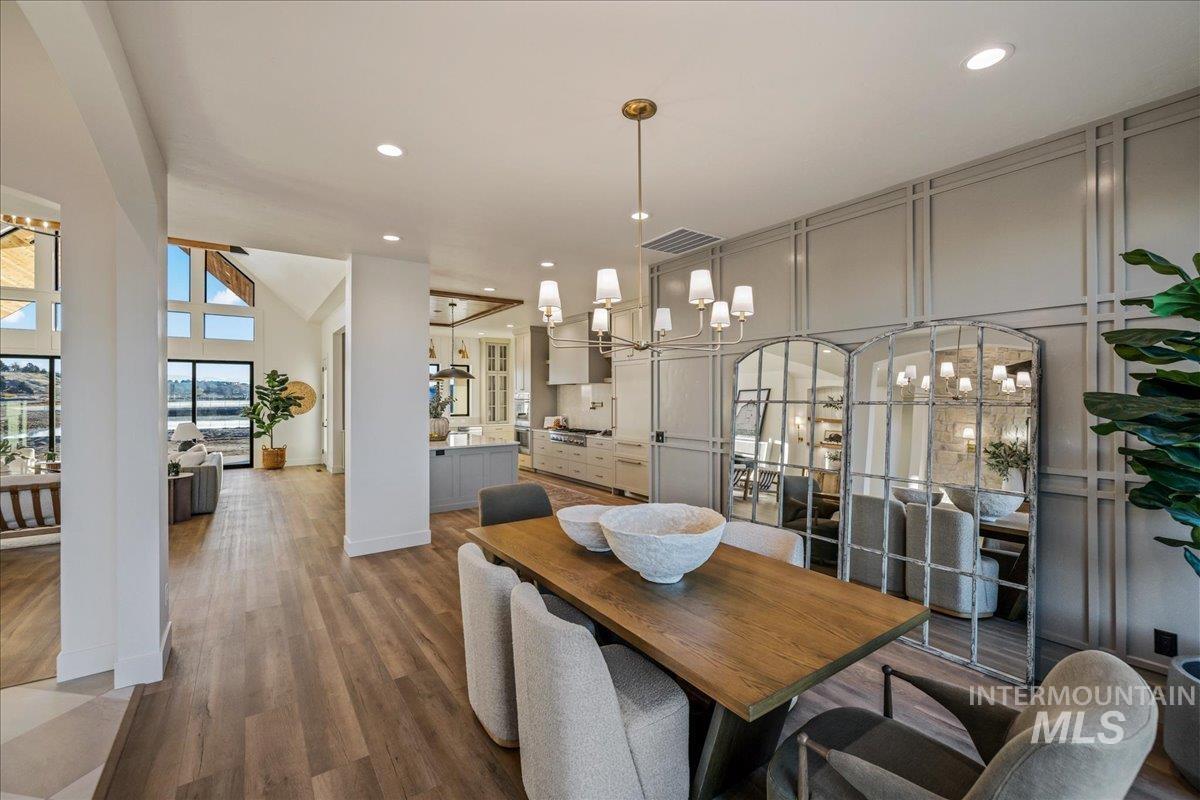 Dining area with a chandelier, dark wood-type flooring, recessed lighting, and a high ceiling