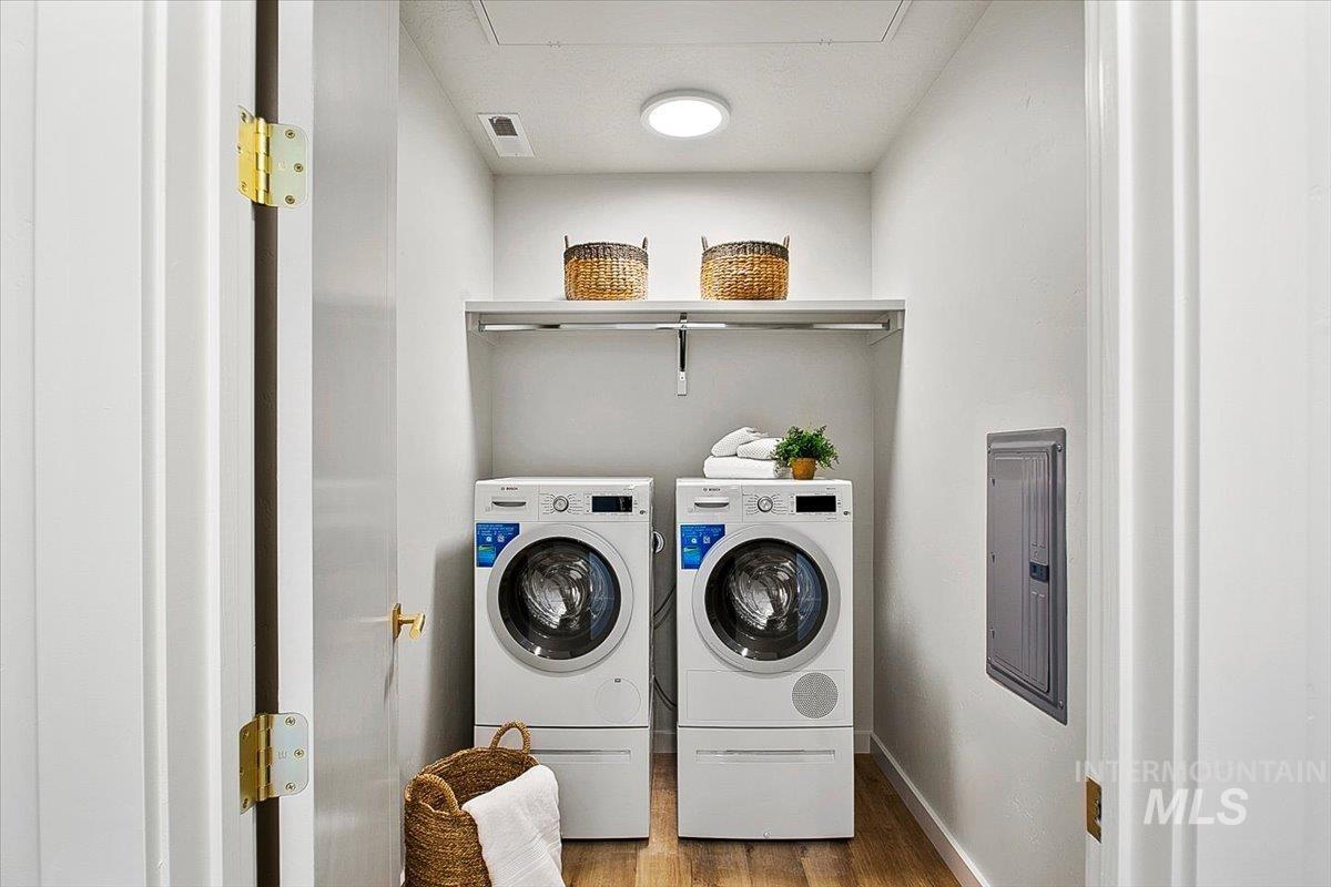 Washroom with wood finished floors, electric panel, and separate washer and dryer
