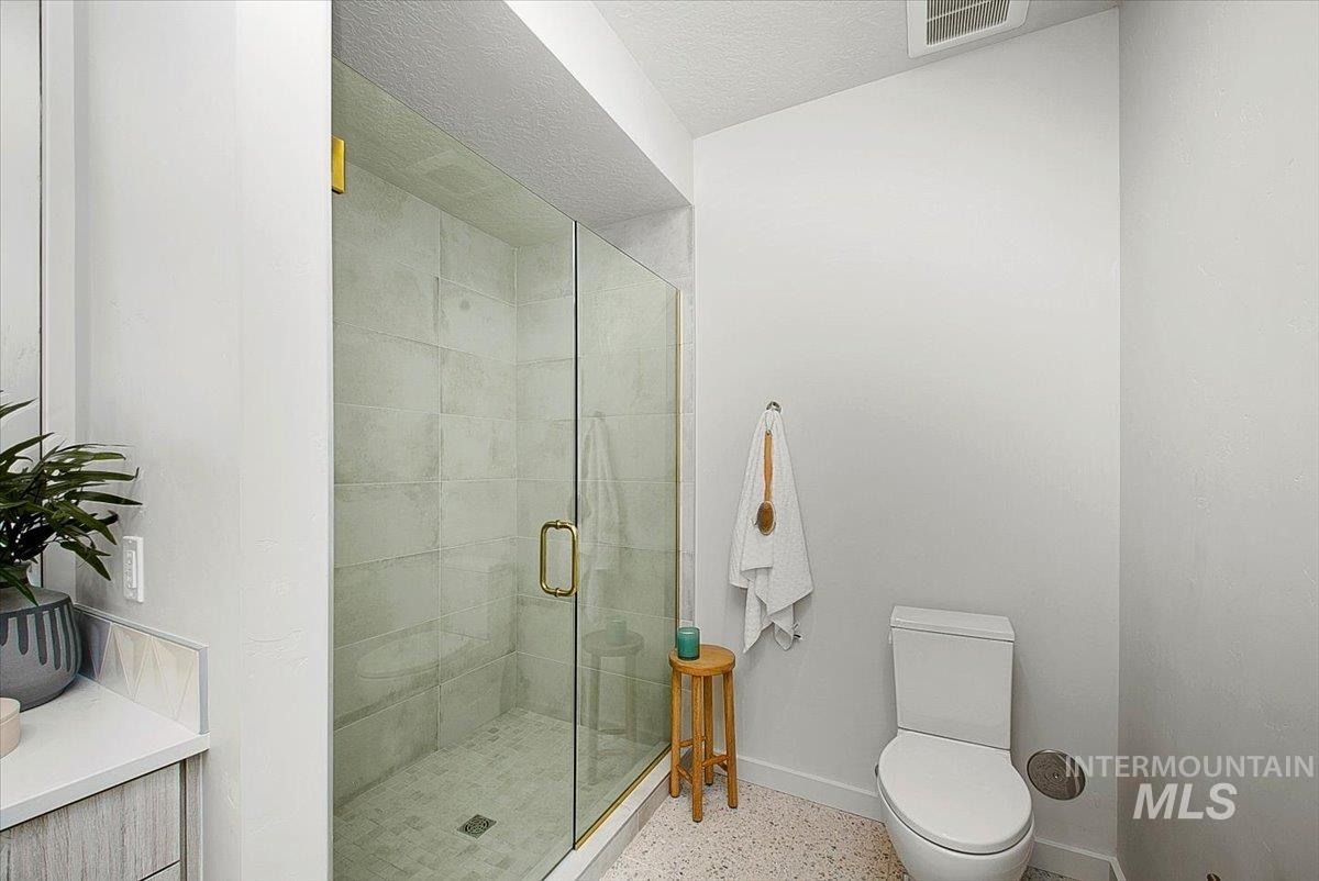 Bathroom with a shower stall and a textured ceiling