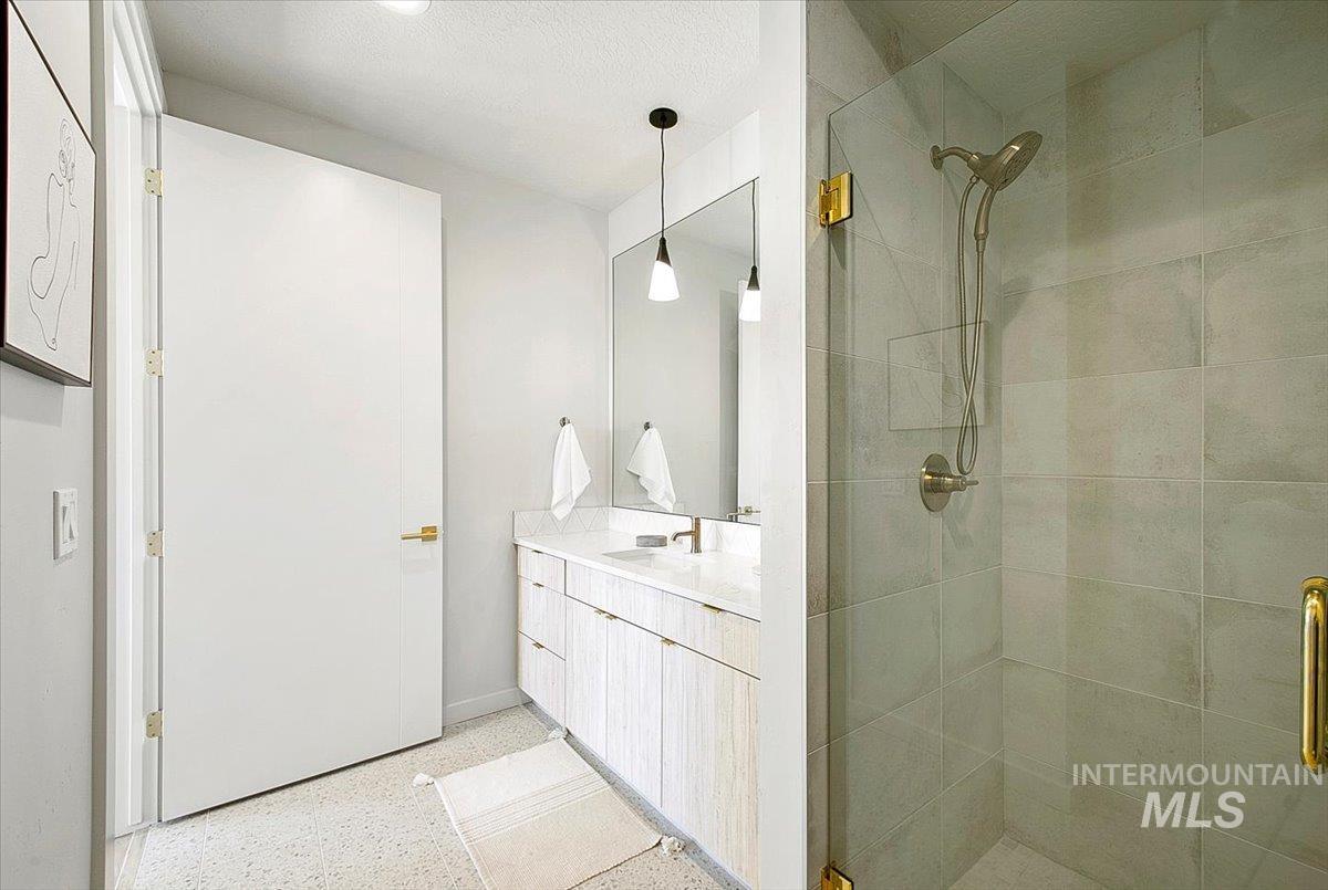 Full bathroom with dark speckled floor, a shower stall, and vanity