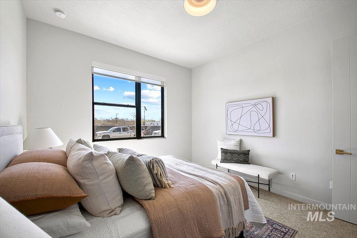 Carpeted bedroom with a textured ceiling and baseboards