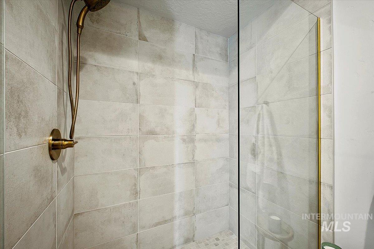 Full bath featuring a shower stall and a textured ceiling