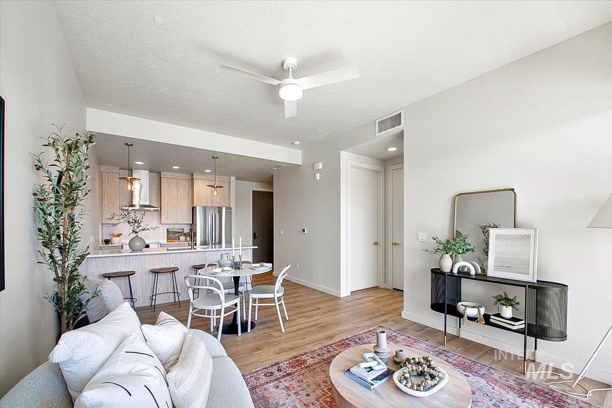 Living room with light wood-type flooring, ceiling fan, and a textured ceiling