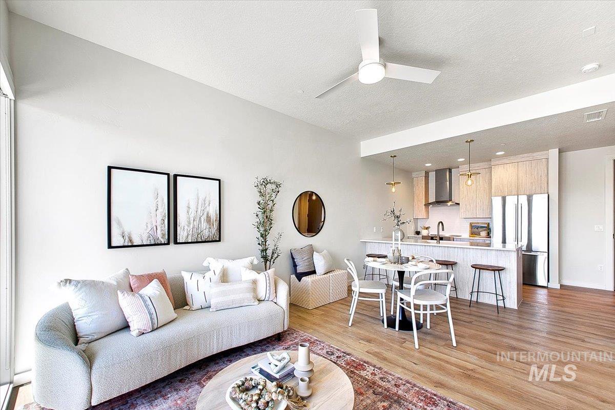 Living room featuring light wood finished floors, a textured ceiling, and ceiling fan