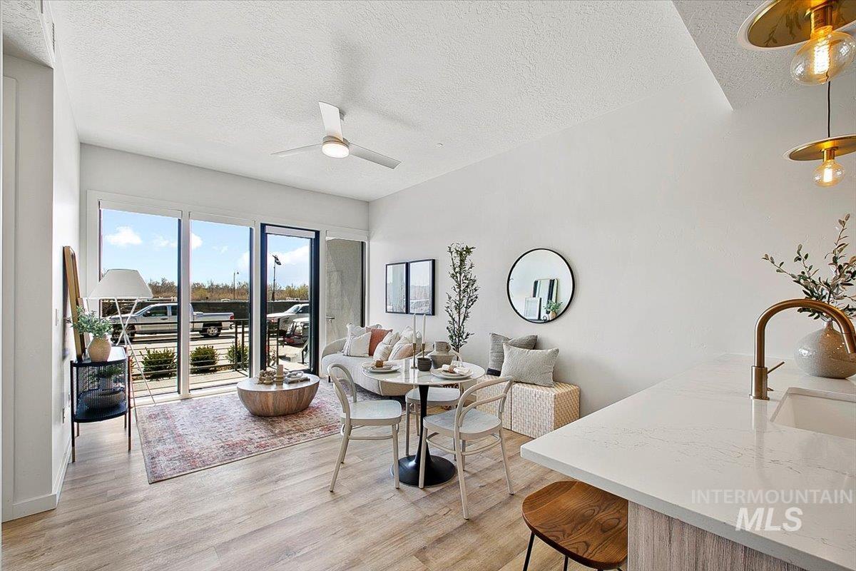 Living area featuring a textured ceiling, light wood-type flooring, and a ceiling fan