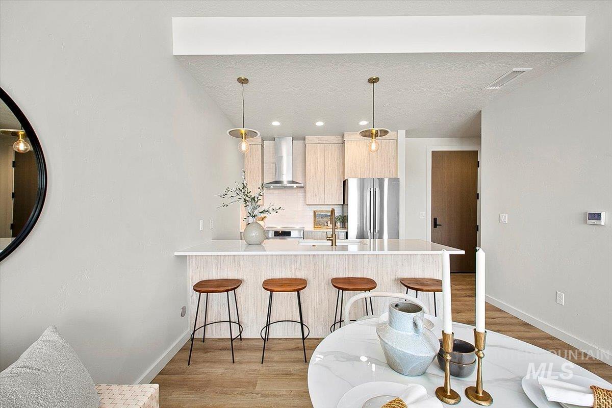 Kitchen with light brown cabinetry, a breakfast bar, a peninsula, modern cabinets, and light wood finished floors